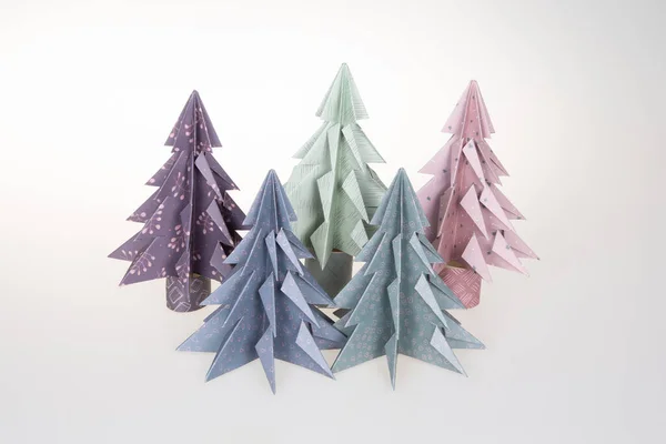 Handmade origami paper craft pine Christmas tree blue green pink on white background