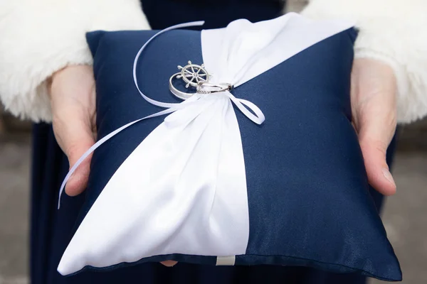 alliance wedding rings hanging on blue white cushions for the married couple