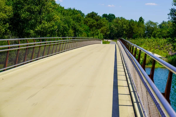 Crossing steel bridge walkway empty with aluminum railing above the river for pedestrians