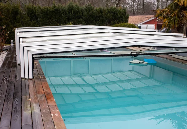 swimming pool with a sliding polycarbonate cover open
