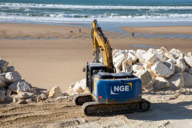 Bordeaux, Aquitaine France - 04 10 2023: NGE Guintoli Excavator turizm sahili mevsimi hazırlığı için kumsalda taş kaydırıyor