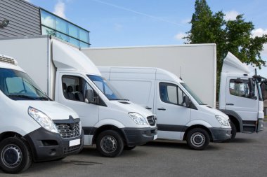 Beyaz teslimat endüstriyel minibüs ve araba fabrika deposunun önünde.