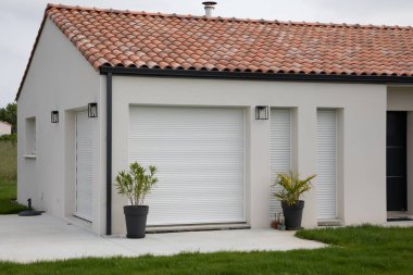 Teraslı modern evin ön cephesi ve yeni banliyö evinin kapalı panjurları.