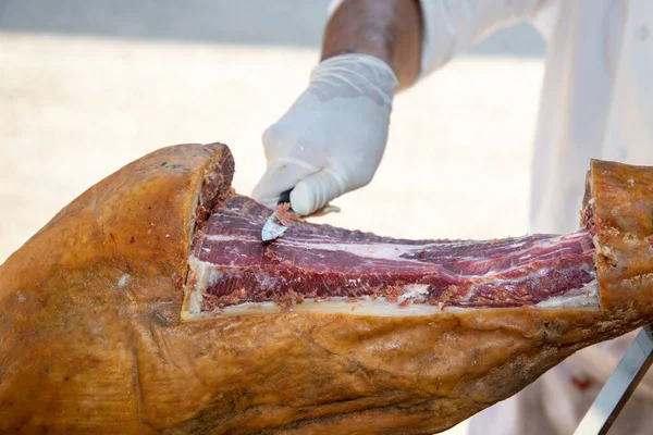 餐桌上的专业厨师手工切伊比利科西班牙猪肉腌制火腿 — 图库照片