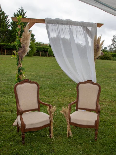 bride and groom old seat chair in summer wedding arch decorated for secular wedding ceremony