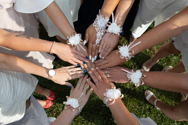 girlfriends of wedding bride hands in a circle hand decorated with flower bracelets