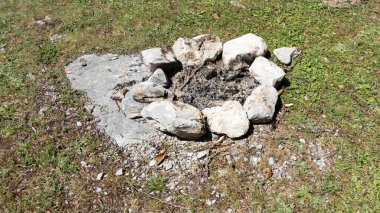 sönmüş ateş çukuru. Etrafı taşlarla çevrili. Çimlerle çevrili. Kamp ateşi üstüne ateş.