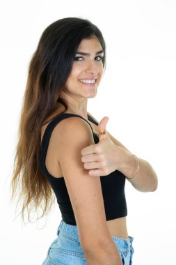 Genç esmer kadın başarısı, el parmağı ile olumlu bir jest imzalar. Beyaz arka planda mutlu bir gülümseme ile gülümser.