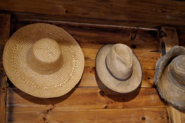 Çiftlik ceketinin askılığında iç duvarda asılı eski hasır şapka.