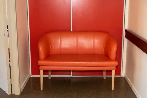 Orange sofa near a textured terracotta wall in minimalist interior corridor
