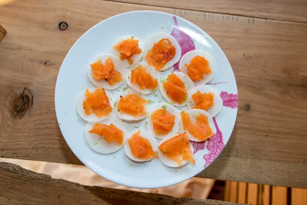 Toasts with smoked salmon on a plate on a wooden table