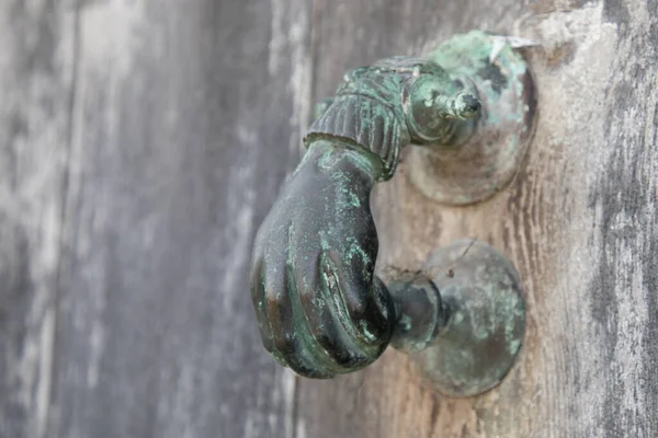 Antique old bronze door knocker in shape of a hand in ancient house
