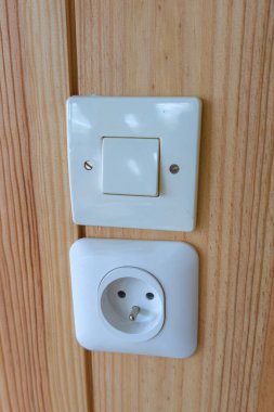 Elektrik prizi için elektrik prizi beyazı ve ahşap duvarda bir anahtar.
