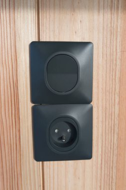 Priz, gri elektrik prizini kapatır ve tahta duvardaki gri ışık düğmesini kapatır.