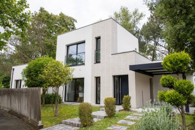 Banliyödeki ev girişinin ön cephesi sokak manzaralı modern beyaz ev.