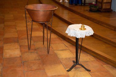 metal font in a church for the baptism of children and baptismal bowl clipart