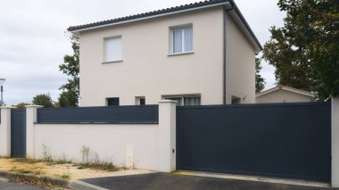 Yeni banliyö evinin büyük gri kapısı olan beyaz modern evin ön cephesi