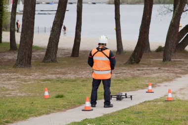 Bordeaux, Fransa - 04 11 2025: İtfaiyeci adam göl kıyısındaki acil durum arabası kurtarma kurbanını filme almak için hava aracı kullanıyor.