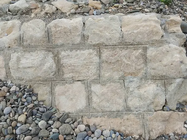 Bu görüntü, titizlikle inşa edilmiş, büyük dikdörtgen bloklar içeren ve gözle görülür tahıl ve dokuya sahip taş bir duvar yakalar. Duvarın bütünlüğü istikrar ve dayanıklılık hissi veriyor. Temelinde, doğal olarak yuvarlak peblerden oluşan bir çeşitlilik var.