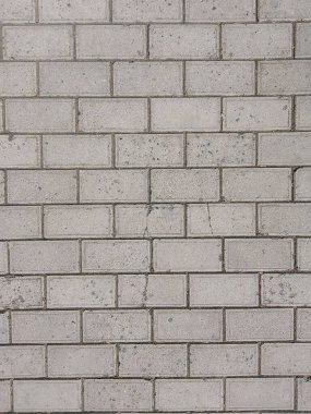 Bu resim, dokulu gri tuğla bir duvarın tam çerçeve arkaplanını gösteriyor. Tuğlalar tek bir şekilde yerleştirilmiş ve hem basit hem de karmaşık bir kalıp oluşturmuş. Griliğin gölgelerinde ince varyasyonlar ve küçük çatlaklar gibi ara sıra aşınma izleri.