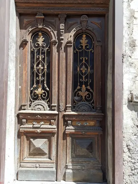 stock image This image captures the rustic charm of a pair of weathered wooden doors, each adorned with intricate ironwork and patterns. The doors stand as a testament to craftsmanship, their aged wood telling stories of years gone by. Despite the peeling paint 