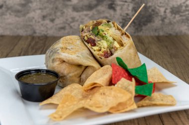 Yumurta, pastırma ve sebze katmanlarını un tortilla ile kaplamak için dolu kahvaltılık burrito ikiye bölünür..