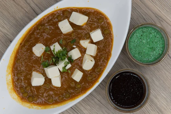 Overhead view of traditional Indian meal starts with a delicious bowl of matar paneer with humus dipping sauce for extra flavor.