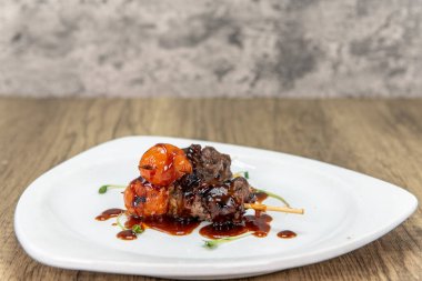 Tempting appetizer of glazed beef skewers served on a small plate.