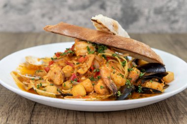 Tempting meal of cioppino with generous amounts of shrimp, mussels, scallops, and clams served on a wide plate.