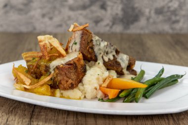 Tempting meal of slow roasted pork belly served with creamy polenta on a generous sized plate.