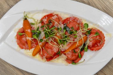 Overhead view of tempting meal of handmade butternut squash ravioli served with romano pecorino cheese.