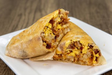 Traditional breakfast burrito with eggs, potatoes, salsa, and cheese all wrapped in a grilled flour tortilla to eat.