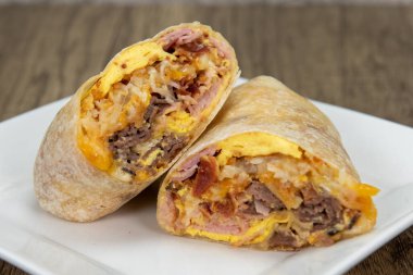 Meat breakfast burrito with eggs, potatoes, baccon, and sausage all wrapped in a grilled flour tortilla to eat.
