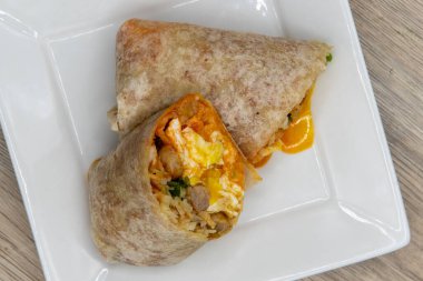 Overhead view of loaded spicy egg and cheese breakfast burrito  all wrapped in a grilled flour tortilla to eat.