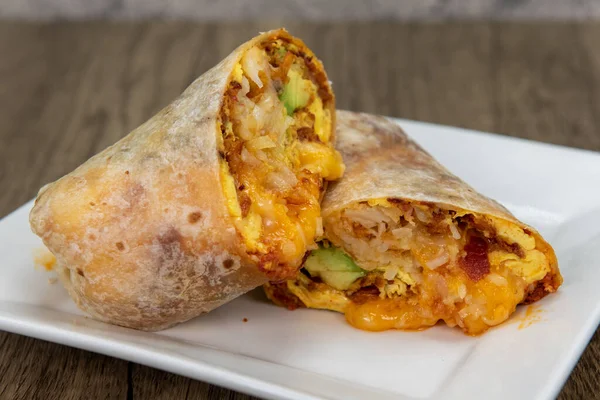 Overhead view of chorizo breakfast burrito with eggs, salsa, and cheese all wrapped in a grilled flour tortilla to eat.