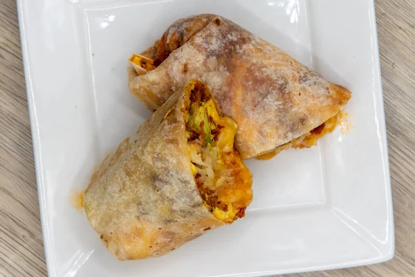 Chorizo breakfast burrito with eggs, salsa, and cheese all wrapped in a grilled flour tortilla to eat.