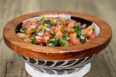 Taze yapılmış pico de gallo salsa Meksika mutfağı sunumu için ahşap bir kasede servis edilir..