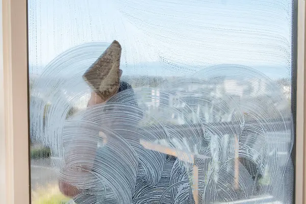 Professional window washer lathers up the window with soapy water to remove the dirt.