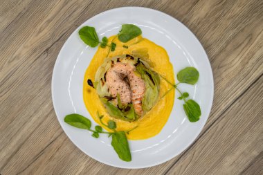 Kabak ve lahanayla servis edilen mükemmel pişirilmiş somon balığı manzarası.