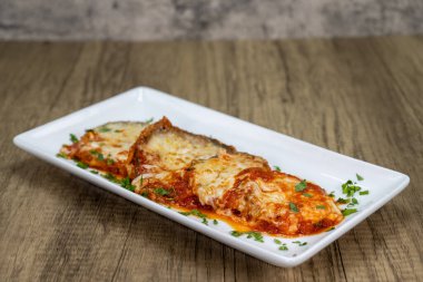 Parmesanlı patlıcan ve mozzarella peyniri bir tabakta servis edilir ve mükemmel pişirilir..