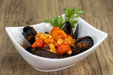 Lezzetli kırmızı soslu cannellini fasulyesiyle servis edilen ve mükemmel pişirilmiş midyelerin genel manzarası..