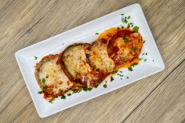 Overhead view of eggplant parmesan and mozzarella cheese served on a plate and cooked to perfection. clipart