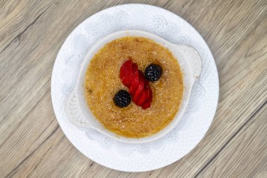 Creme brulee tatlısının genel manzarası üzerinde dilimlenmiş çilek ve böğürtlen ile servis edilir..