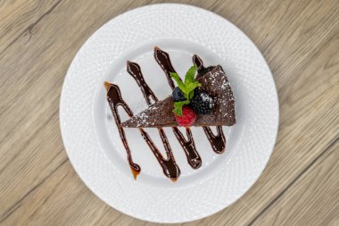 Meyve soslu acı çikolatalı pasta ve tatlı olarak çikolatalı süsleme manzarası..