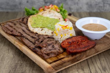 Izgara carne asada dilimlenmiş et yemeği pilav, sucuk ve fasulye ile servis edilir..