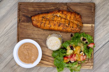 Tavanda ızgara zarandeado fileto, pirinç ve fasulyeyle servis edilen ahşap tabakta..