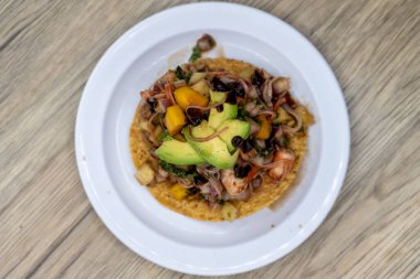 Lezzetli görünümlü tostada egzotik bir tortilla üst üste istiflenmiş ve mükemmel bir Meksika deniz ürünleri yemeği için doğranmış meyve ve avokado ile kaplı.