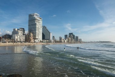 Sörfçüler dalgaları yakalamak için Tel Aviv sahillerinde suya girerler.