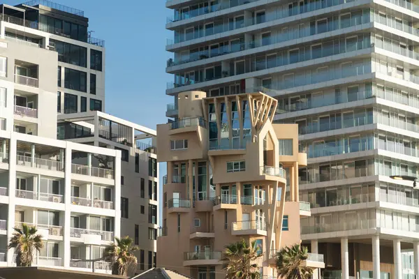 Tel Aviv, İsrail - 07 Mart 2024: Deniz kenarında soğuk bir tasarımı olan alışılmadık bir alçak bina, arkasında devasa modern kuleler yükselirken,