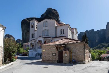 Kastraki, Yunanistan - 30 Nisan 2025: St. Athanasius 16. yüzyıl Kilisesi, sonsuz mavi gökyüzüne karşı Meteora 'nın yükselen kaya oluşumları tarafından çerçevelenmiş güneş ışığıyla güneşleniyor